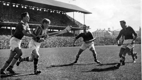 Mark Marnell brings out the ball through a cluster of Cork forwards in the 1947 Final.